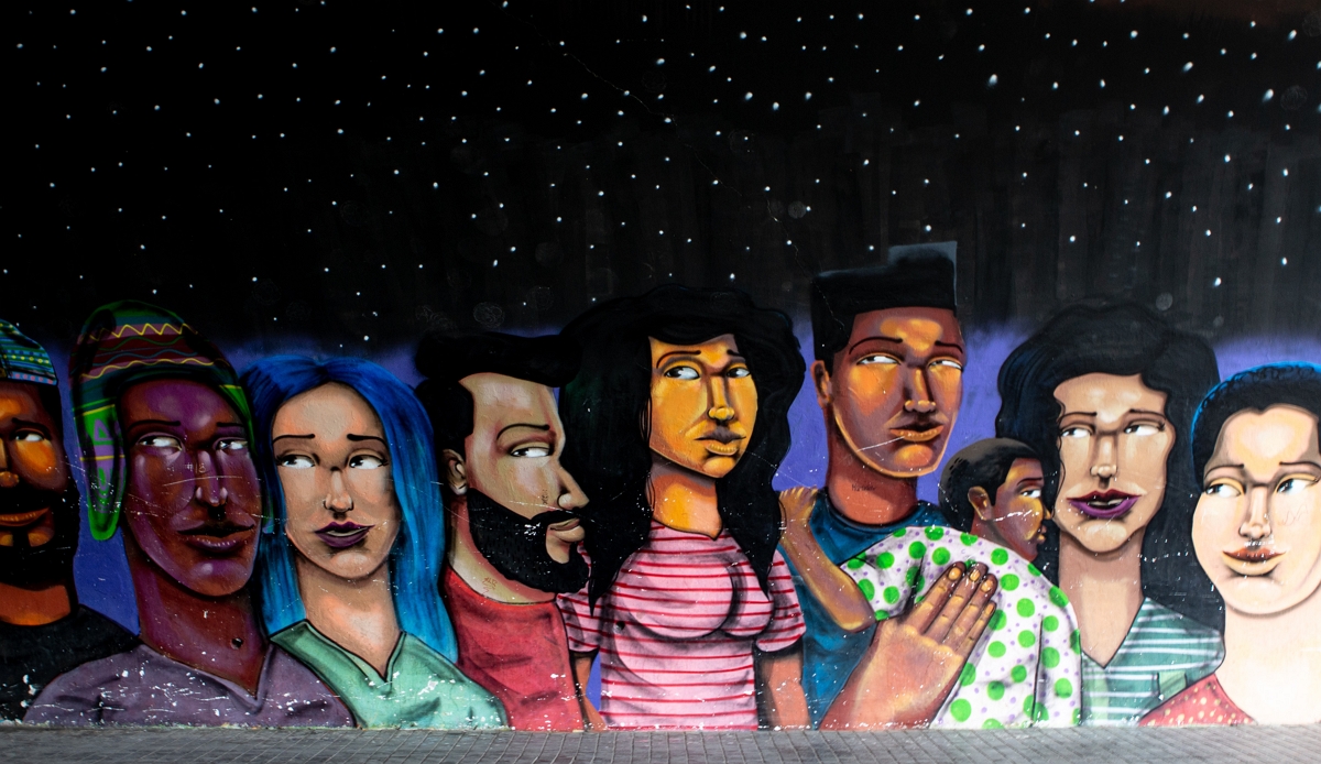 Wandgraffity einer Grupper unterscheidlicher Mesnschen vor einem Sternenhimmel