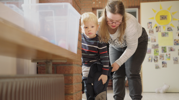 Eine Frau mit Downsyndrom hilft einem Kleinkind
