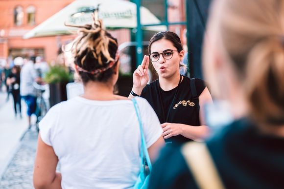 Gebärdensprache Zwei Frauen in städtischer Umgebung unterhalten sich in Gebärdensprache